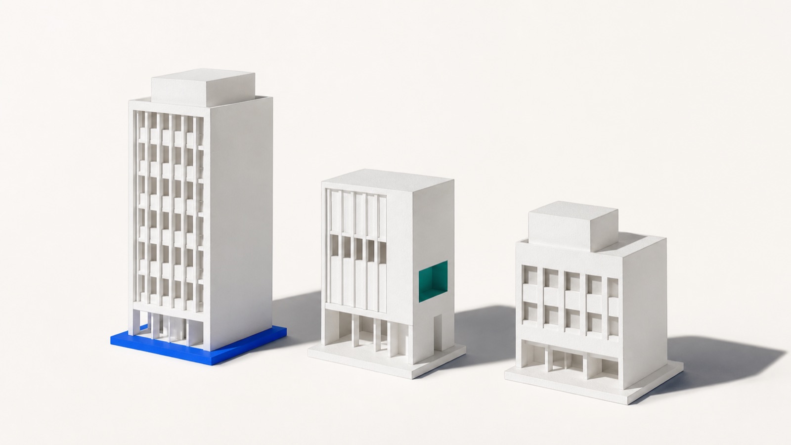 Three white architectural building models standing on a blue base